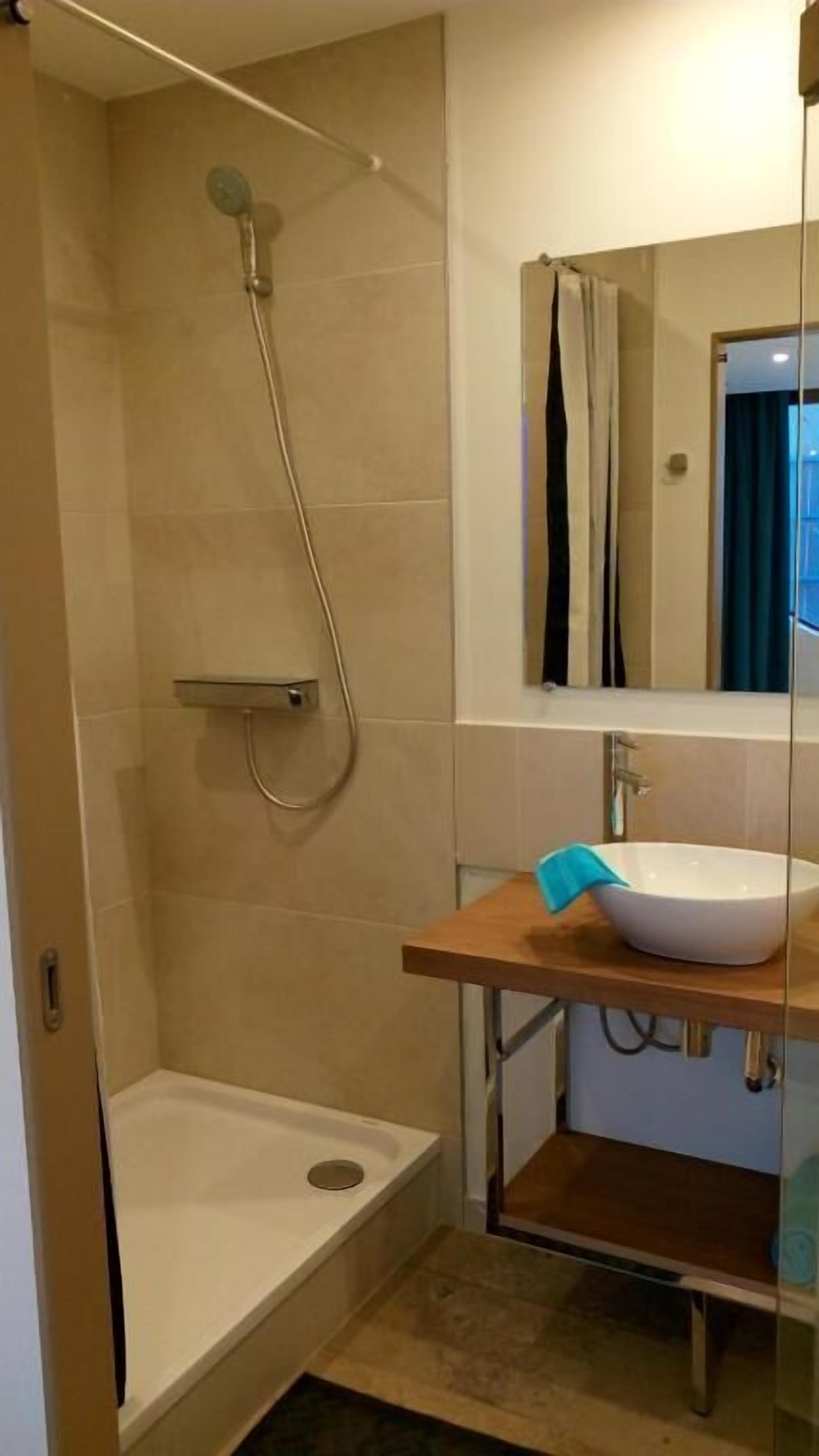 Een moderne badkamer met een douche, een wastafel en een spiegel.