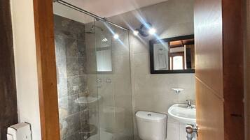 A modern bathroom with a glass-enclosed shower, a toilet, and a sink.
