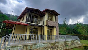 A two-story house with a balcony, a stone pathway, and a grassy lawn. - Forest House (Salento)