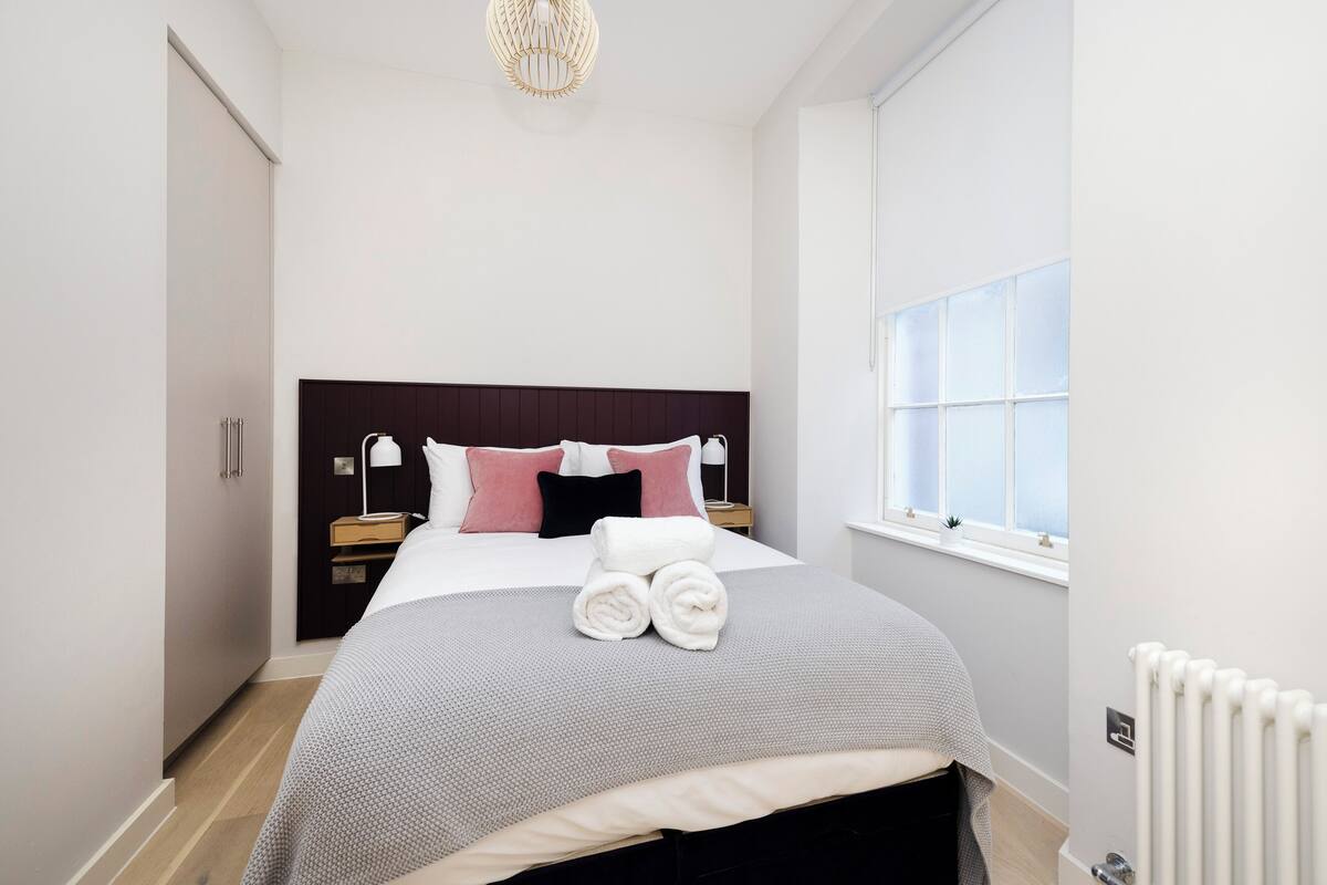 Un dormitorio moderno con una cama grande, una mesita de noche y una ventana con vistas.