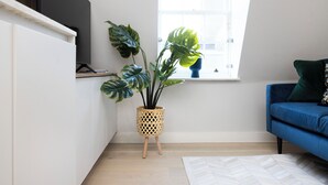 En moderne stue med en blå sofa, en potteplante og et vindue med udsigt.