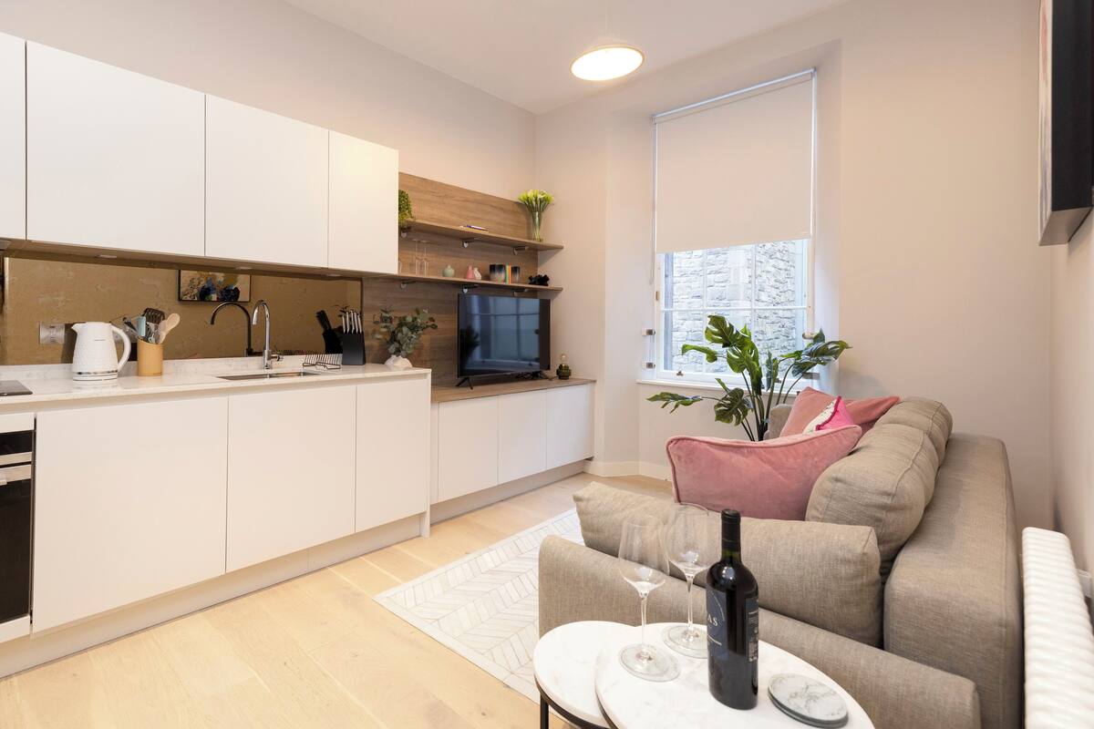 Una cocina moderna con armarios blancos, un refrigerador negro y un ventanal con vistas.