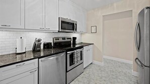 Una cocina moderna con armarios blancos, electrodomésticos de acero inoxidable y encimera negra.
