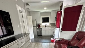 A modern kitchen with white cabinets, a stainless steel refrigerator, and a built-in dishwasher.