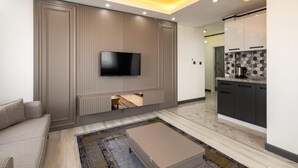 Ein modernes Wohnzimmer mit Flachbildfernseher, einer Couch und einem Couchtisch.