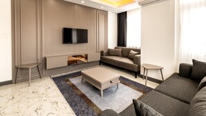 Ein modernes Wohnzimmer mit Flachbildfernseher, Ecksofa, Couchtisch und gemustertem Teppich.