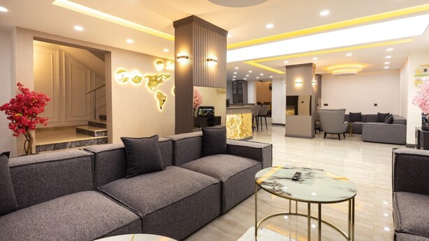 Eine moderne Hotellobby mit einem grauen Sofa, einem Marmortisch und einer Weltkarten-Leuchtkunstinstallation.