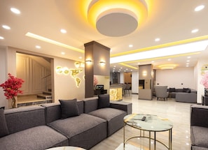 A modern hotel lobby with a grey sofa, a marble coffee table, and a world map light installation. - selia suite (Trabzon)