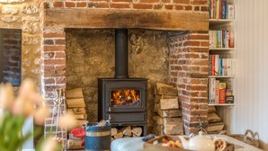 A cozy room with a brick fireplace, a bookshelf, and a comfortable seating area. - Ivy Cottage - sleeps 6 guests  in 3 bedrooms (Thornham)