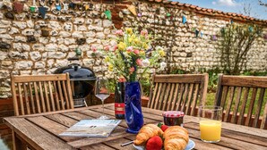 A wooden table with a plate of croissants, strawberries, and a glass of orange juice, a bottle of wine, and a vase of flowers. - Ivy Cottage - sleeps 6 guests  in 3 bedrooms (Thornham)
