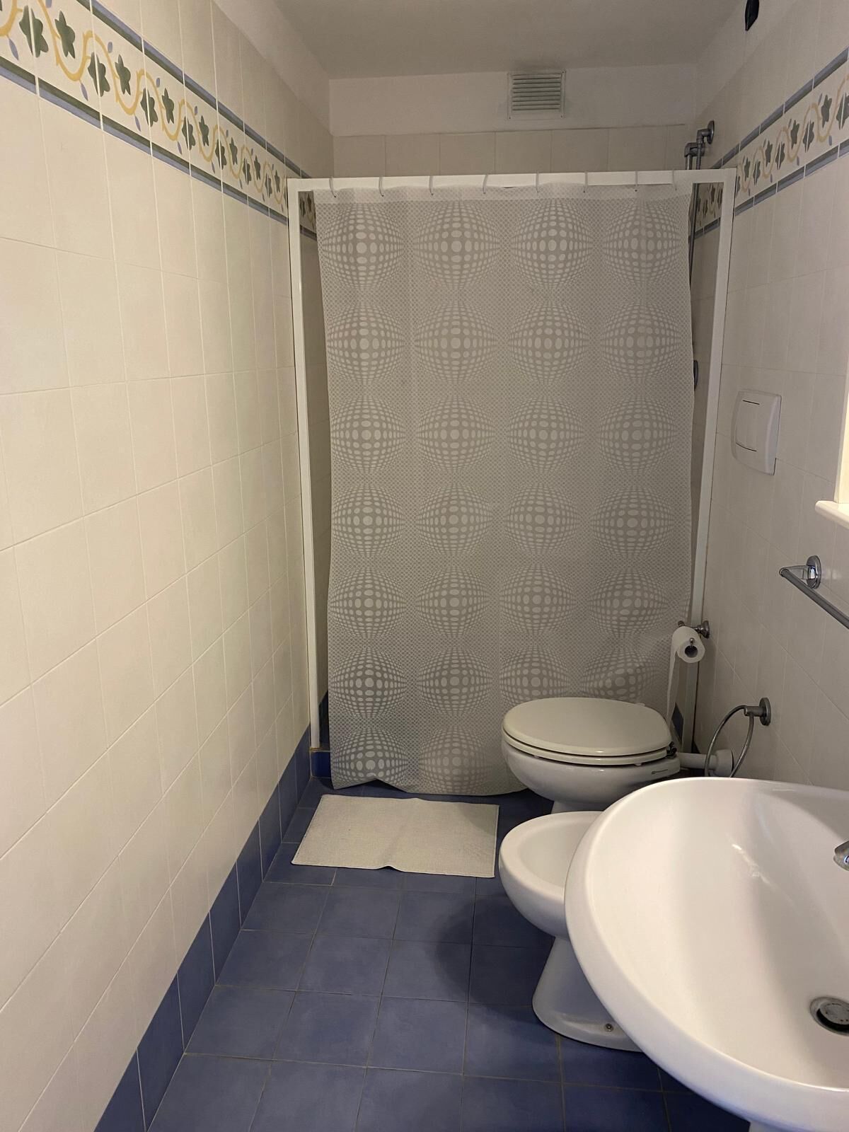A bathroom with a toilet, a sink, and a shower curtain with a geometric pattern.