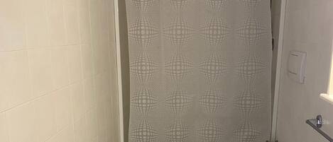 A bathroom with a toilet, a sink, and a shower curtain with a geometric pattern.