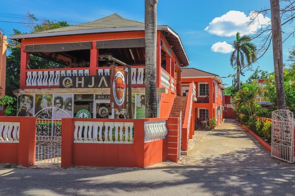 A two-story building with a red facade, a balcony with a white railing, and a sign that reads "OHJA". - Spacious boutique hotel with 12 en-suites and WiFi, AC in delightful Negril (Negril)