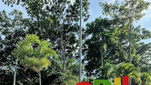 A landscaped area with large, colorful letters spelling "NEGRIL" on a stone platform, surrounded by grass and trees.
