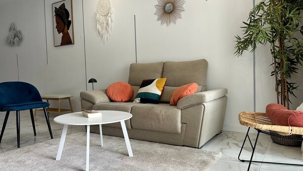 A living room with a grey sofa, a round white coffee table, a blue chair, and a small side table.