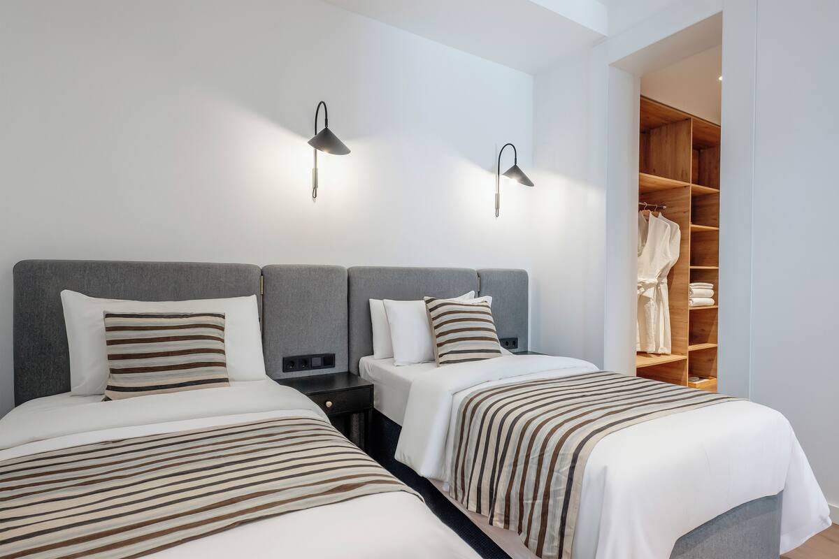 Ein Hotelzimmer mit zwei Betten, einem Kleiderschrank und zwei Wandlampen.