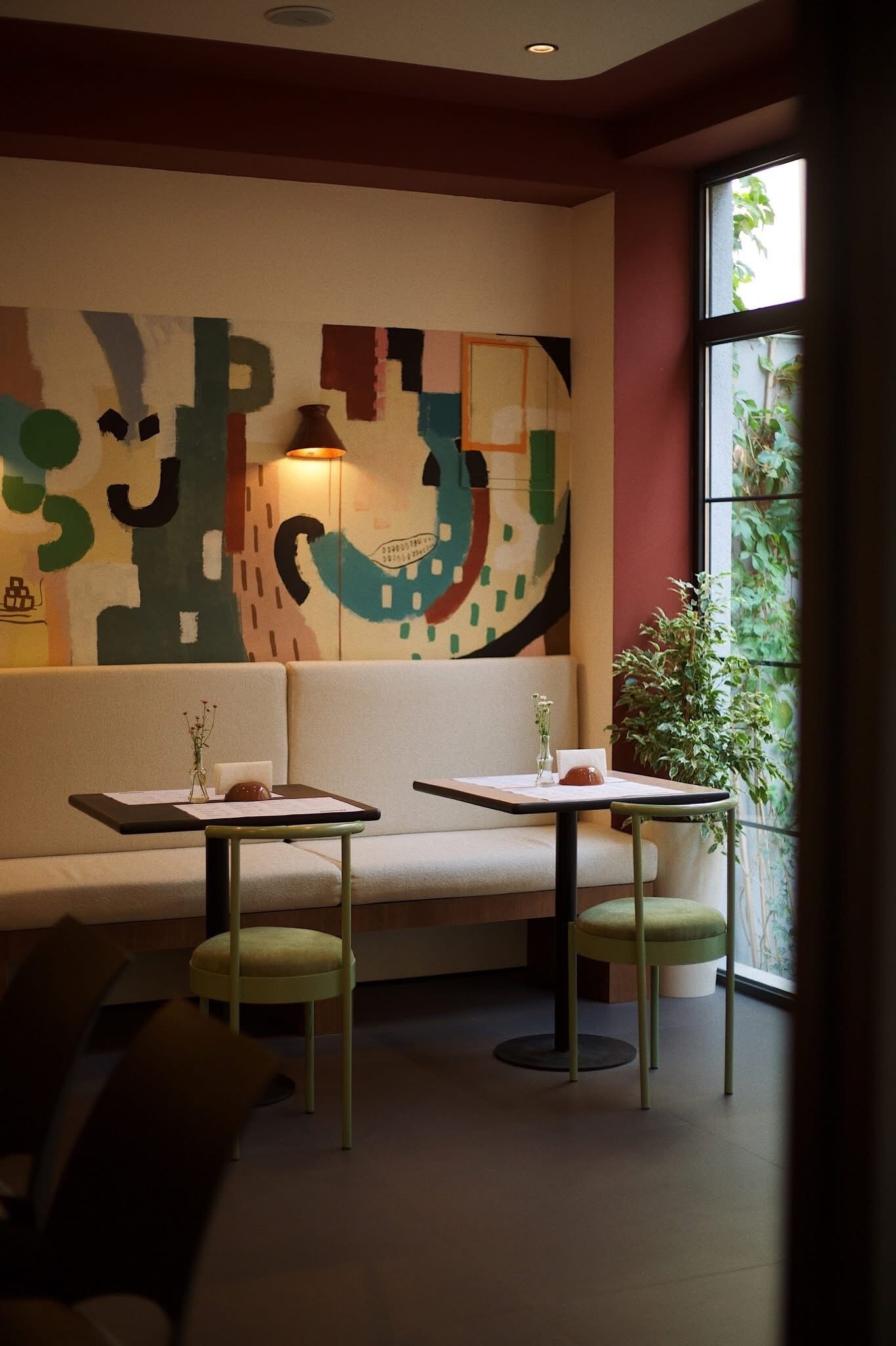 Un interior moderno con un sofá, dos mesas y un cuadro abstracto grande en la pared.