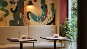 Un interior moderno con un sofá, dos mesas y un cuadro abstracto grande en la pared.