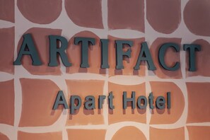 A sign for the ARTIFACT Apart Hotel with a geometric pattern background. - Artifact Apart Hotel  (Tbilisi)
