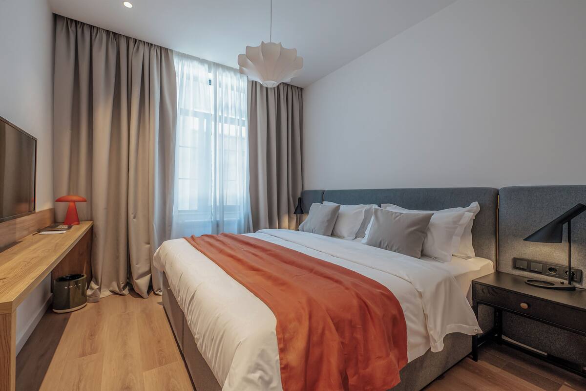 Ein modernes Hotelzimmer mit einem großen Bett, einem Schreibtisch und einem Nachttisch.