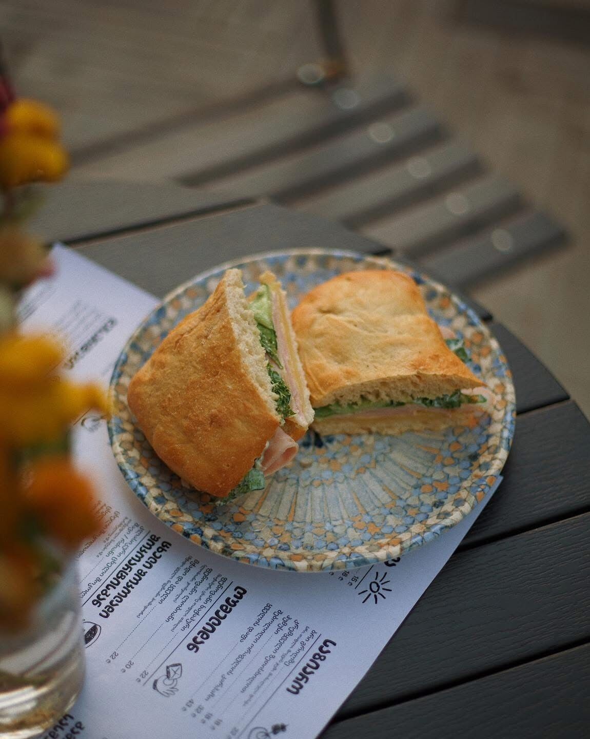A sandwich on a plate with a menu underneath.