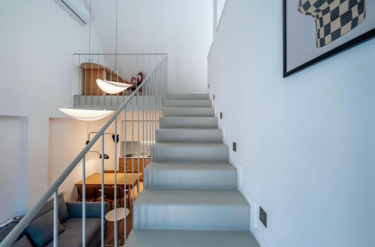 Eine moderne Treppe mit minimalistischem Design, ein Essbereich mit Holztisch und Stühlen sowie ein gerahmtes Kunstwerk an der Wand.