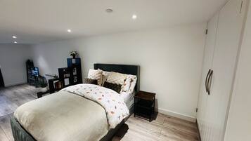 A modern bedroom with a bed, bedside tables, a TV, and a wardrobe.