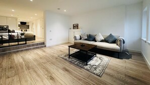Ein modernes Wohnzimmer mit Sofa, Couchtisch und einer Treppe zu einer oberen Etage.