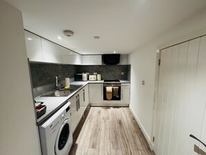 A compact kitchen with a washing machine, a microwave, a toaster, and a sink. - Ash Residence City Centre
A stunning warm and cozy city center apartment. (Aberdeen)