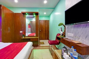 Una habitación de hotel con cama, escritorio, silla, televisor y un mostrador de recepción.