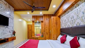 Ein Schlafzimmer mit Bett, Fernseher, Holzschrank und Deckenventilator.