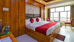 Ein Hotelzimmer mit einem großen Bett, einem Holzkopfstück und Blick ins Freie durch ein Fenster.