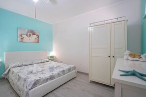 A bedroom with a bed, a wardrobe, a bedside table with a starfish decoration, and a wall-mounted light fixture. - Riva Di Mare Apartment With Balcony Near The Sea (Porto Cesareo)