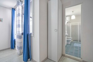 Une salle de bain avec une douche, des toilettes et une fenêtre avec un rideau.