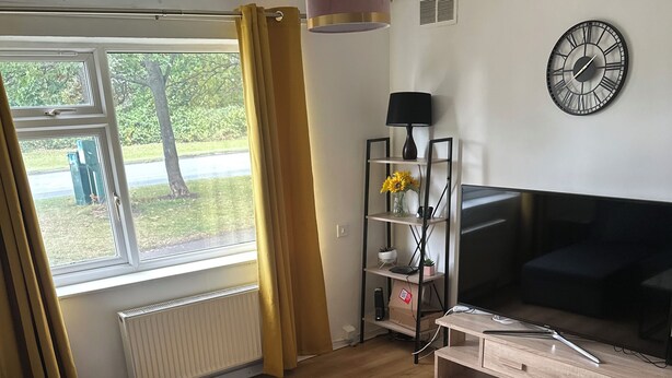 Un salon comprenant un canapé, une table basse, un téléviseur et une étagère ornée d’objets décoratifs.