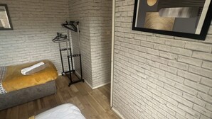 Une chambre avec deux lits, un porte-manteau et un tableau encadré au mur.