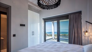 Een moderne hotelkamer met een groot bed, uitzicht op zee en een balkon.