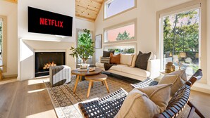 Un salon moderne avec une cheminée, un canapé, une table basse et un téléviseur fixé au mur.