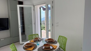 Uma sala de jantar com uma mesa posta para quatro, cadeiras e uma televisão ao fundo.