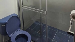 A bathroom with a glass-enclosed shower, a blue toilet, and a white sink. - Loft Type Apartment. Bogotá Concejo (Bogotá)