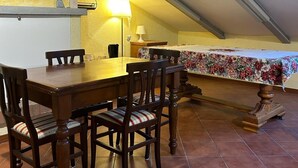 Uma área de refeições com uma mesa e cadeiras de madeira, um abajur e uma cama com colcha florida.