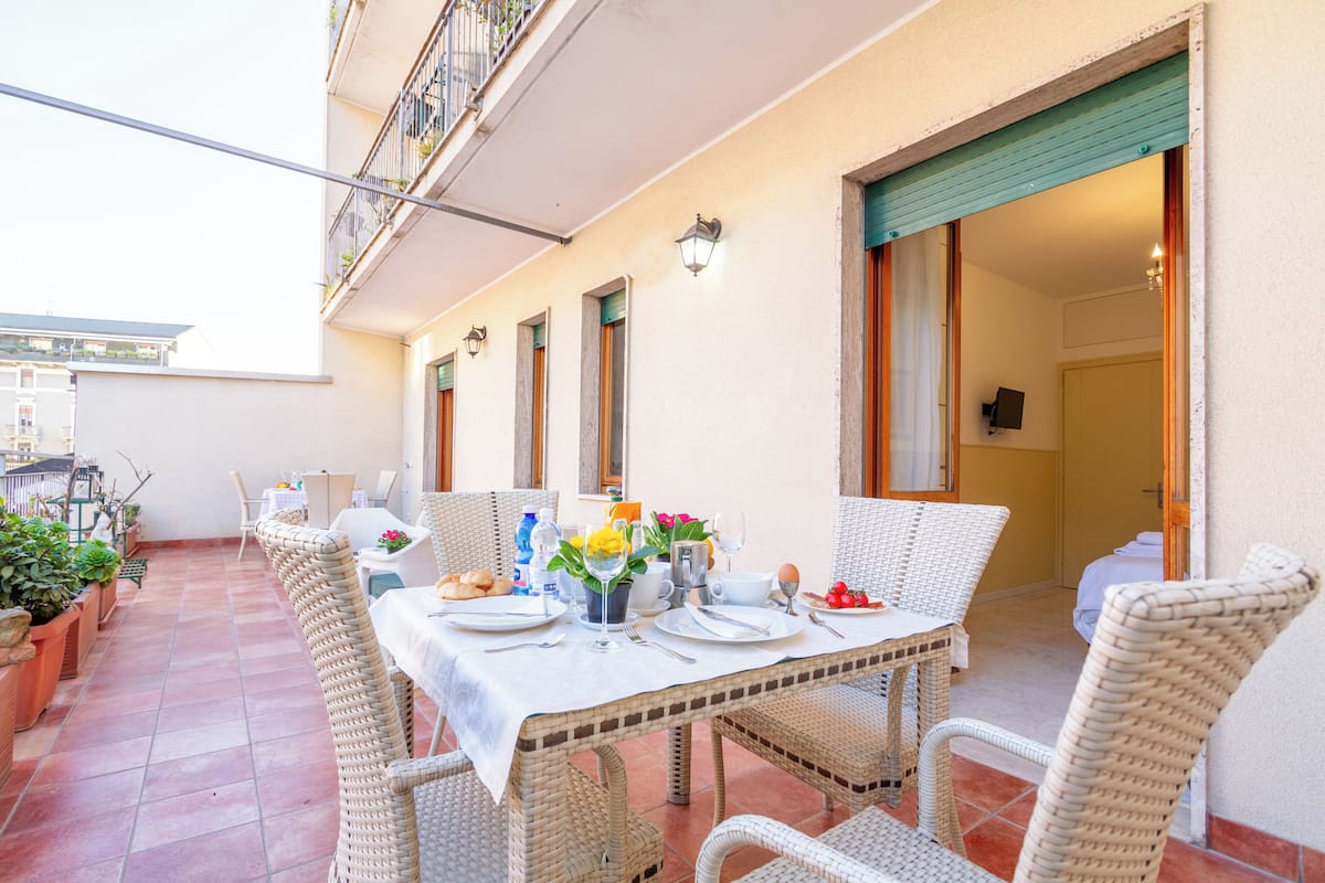Un comedor con sillas de mimbre y una mesa dispuesta para una comida, con mantel blanco y diferentes platos.