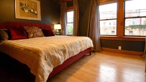 A bedroom with a large bed, a red headboard, and a window with curtains. - "City View " super cozy downtown Loft apartment (Bloomington)