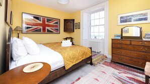 A bedroom with a bed, a dresser, a mirror, and a window. - Inviting Flat near City Centre (Edinburgh)
