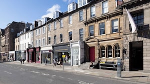 A street view with buildings, including a shop named "The Cambridge Sarcophagus Company" and a sign for "Calathor to Let." - Inviting Flat near City Centre (Edinburgh)