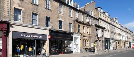 A street view with a row of buildings, including a store named "Helly Hansen" and a company named "The Cambridge Satchel Company".