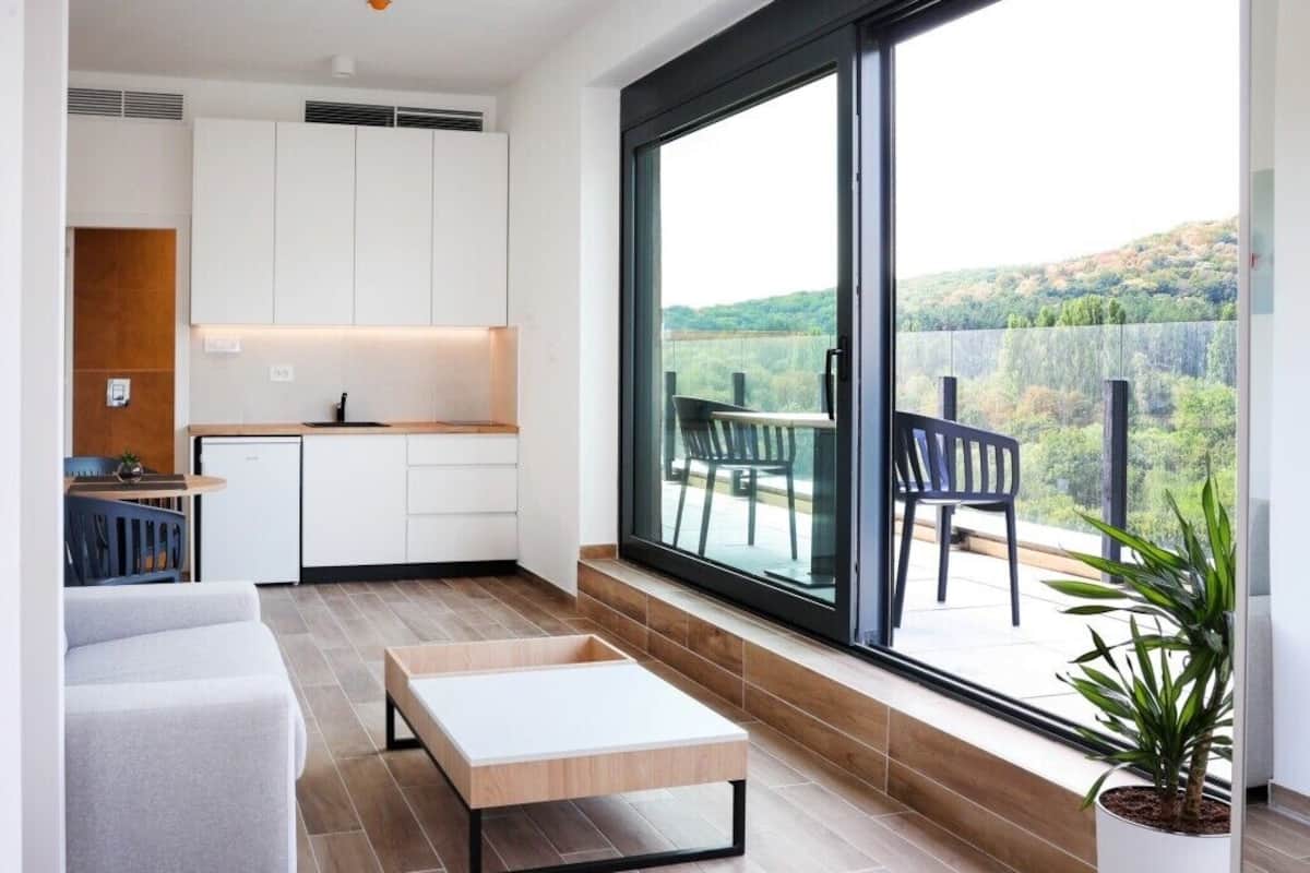 Una cocina moderna con armarios blancos, un comedor con banco y un amplio ventanal con vistas a un paisaje pintoresco.