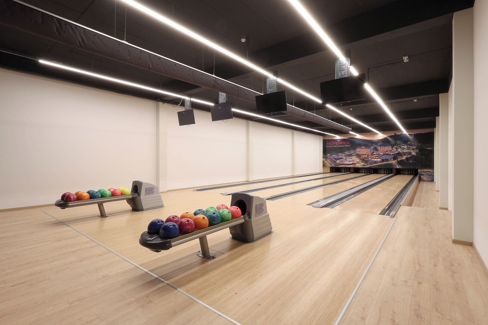 Une salle de bowling dotée de nombreuses pistes, d’un plancher en bois et d’un éclairage au plafond.