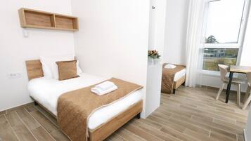 A modern hotel room with a wooden bed, a small desk, and a window with a view.