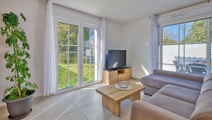A modern living room with a large window, a flat-screen TV, a wooden coffee table, and a sofa.
